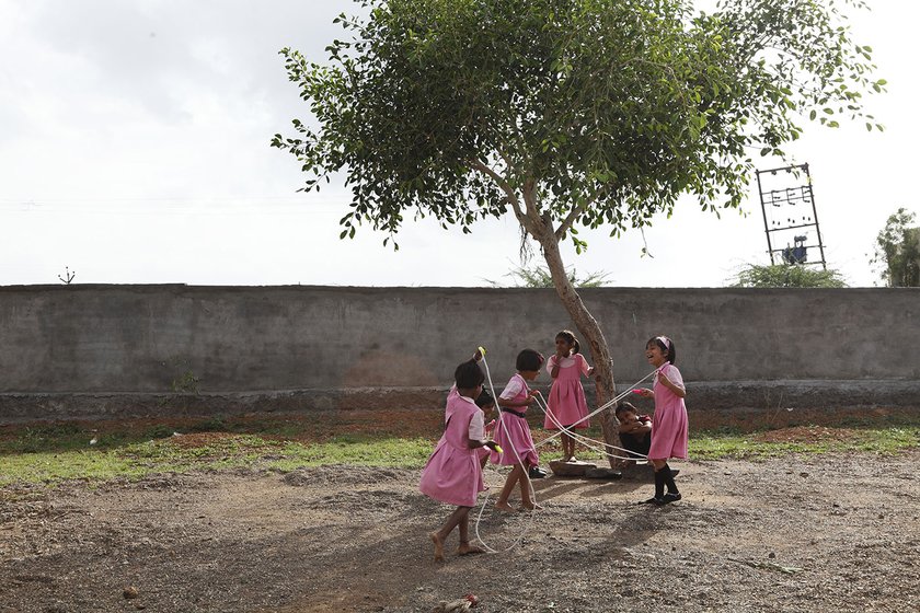 Girls skipping under the tree on their school playground  