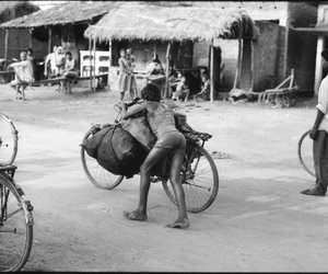 Young boy pushing coal laden cycle from behind