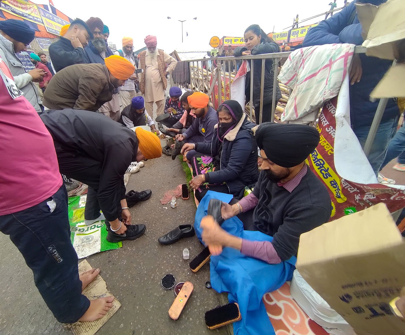 Unmindful of the dust, dirt and occasional rain, Jaswinder Singh Saini and Prakash Kaur, a couple from Delhi, perform sewa at Singhu – cleaning the dirty, muddied shoes of the farmers