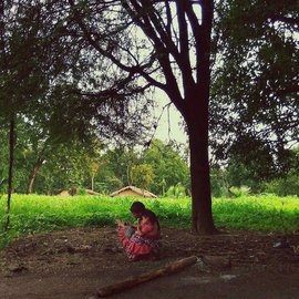 A woman with her child under a mahua tree in Farsegarh village, Bijapur district; she is a forest dependent farmer who was returning from the weekly market or haat with her child