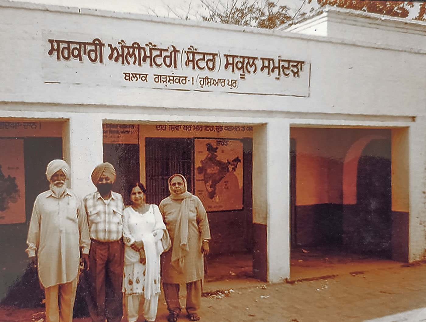 Bhagat Singh Jhuggian and his wife Gurdev Kaur, with two friends in between them, stand in front of the school, since renovated, that threw him out in 1939