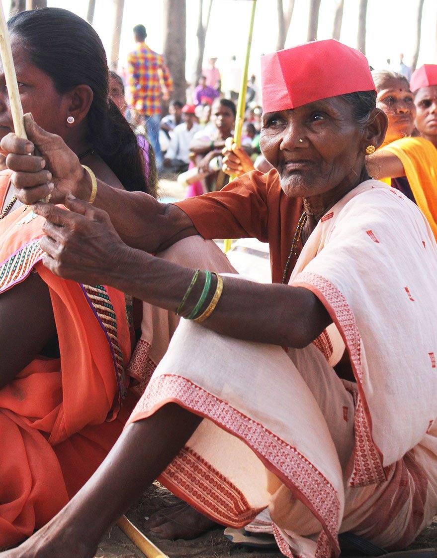 A woman sitting on a beach holding the All India Kisan Sabha flag