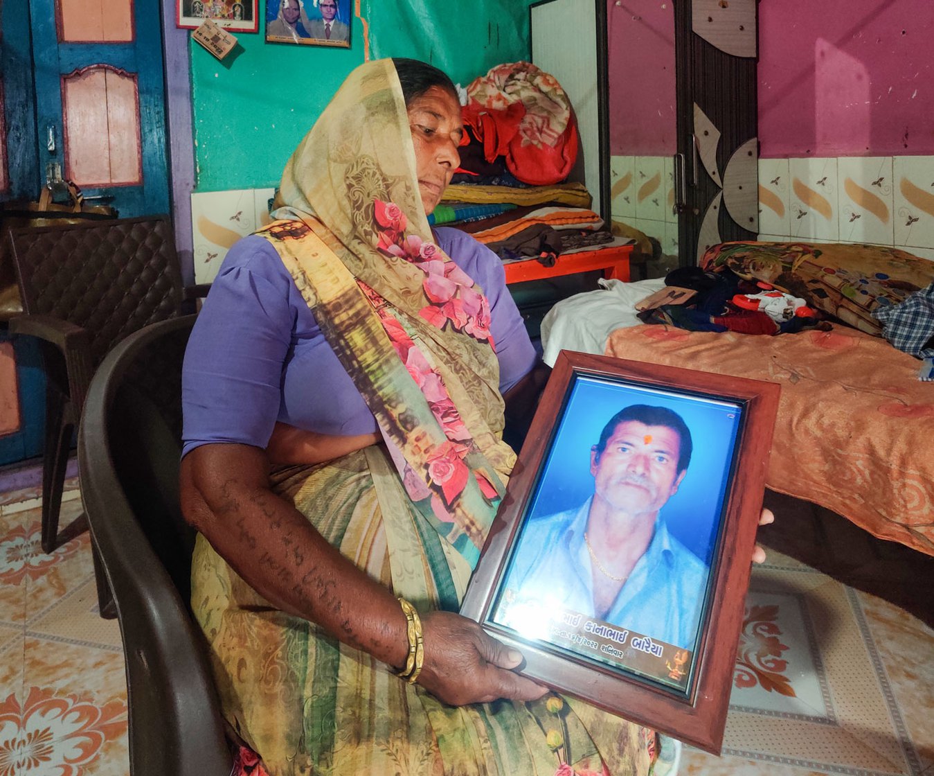 Gabhiben holding a portrait of her late husband, Jeevanbhai, at their home in Jafrabad, a coastal town in Gujarat’s Amreli district