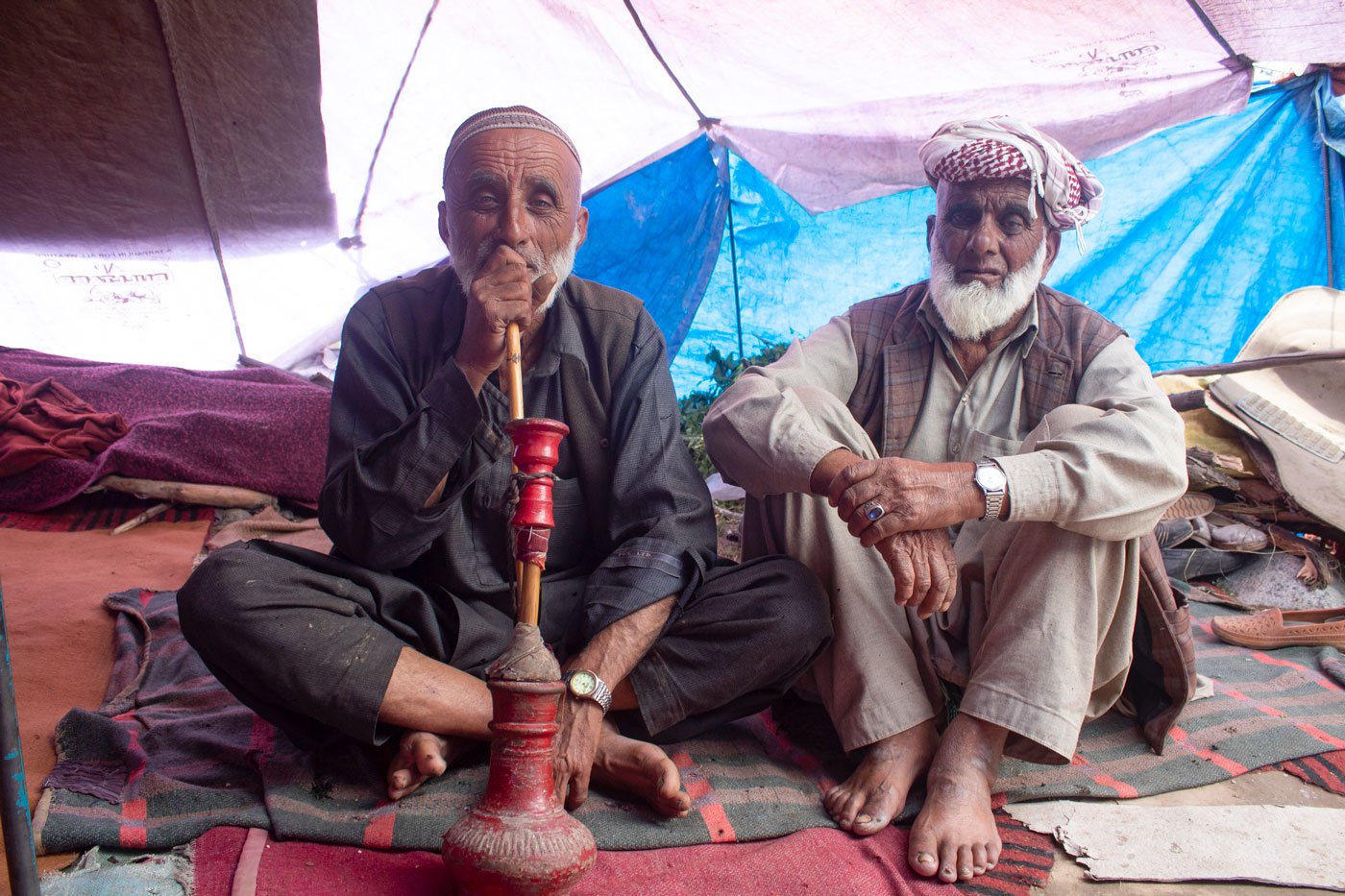 Abdul Latief Bajran (left) migrated out of his village, Peri in Rajouri district, in early May with his 150 animals – sheep, goats, horses and a dog – in search of grazing grounds high up in the mountains of Kashmir. Seated with Mohammad Qasim (right) inside a tent in Wayil near Ganderbal district, waiting to continue his journey