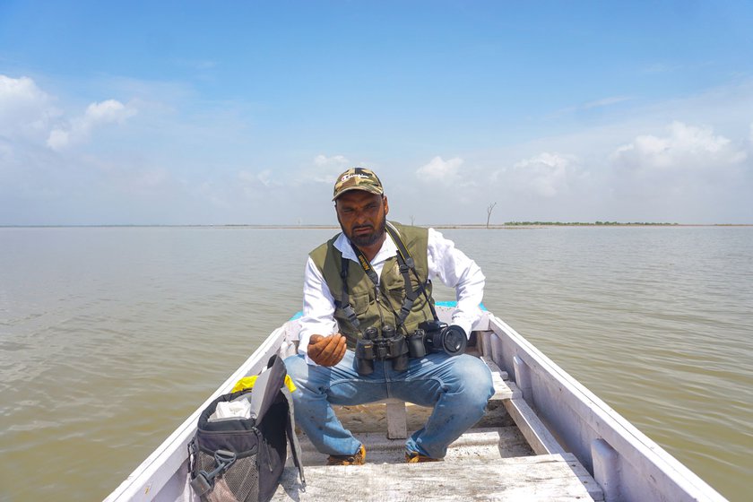 Gani on a boat with his camera equipment, looking for birds to photograph on the Nal Sarovar lake in Gujarat