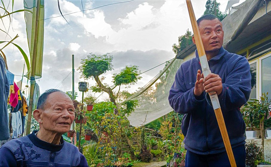 Left: Tshering Dorjee with pieces of the stick that are joined to make the traditional tabjoo bow. Right: His elder son, Sangay Tshering (right), shows a finished tabjoo