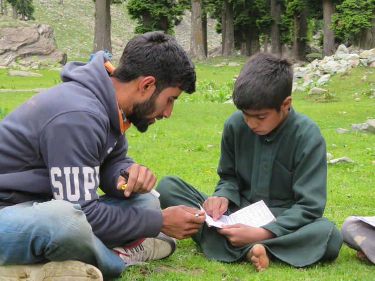 Right: Ali Mohammed explaining the lesson to Ejaz. Both students have migrated with their parents to Khalan, a hamlet in Lidder valley