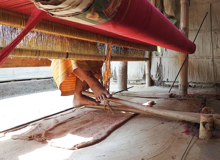 Sama seated at her bamboo pedal loom