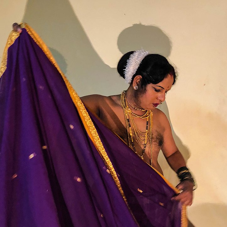 A male actor playing a female role. He is folding a sari