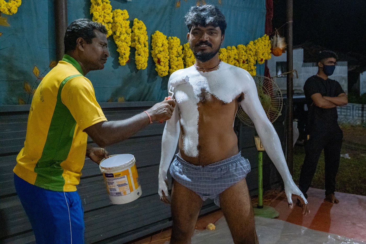 Ramzan paints Ashwith Poojari ahead of the performance. A clay model artist by profession, Ramzan lends a hand to performances during the season
