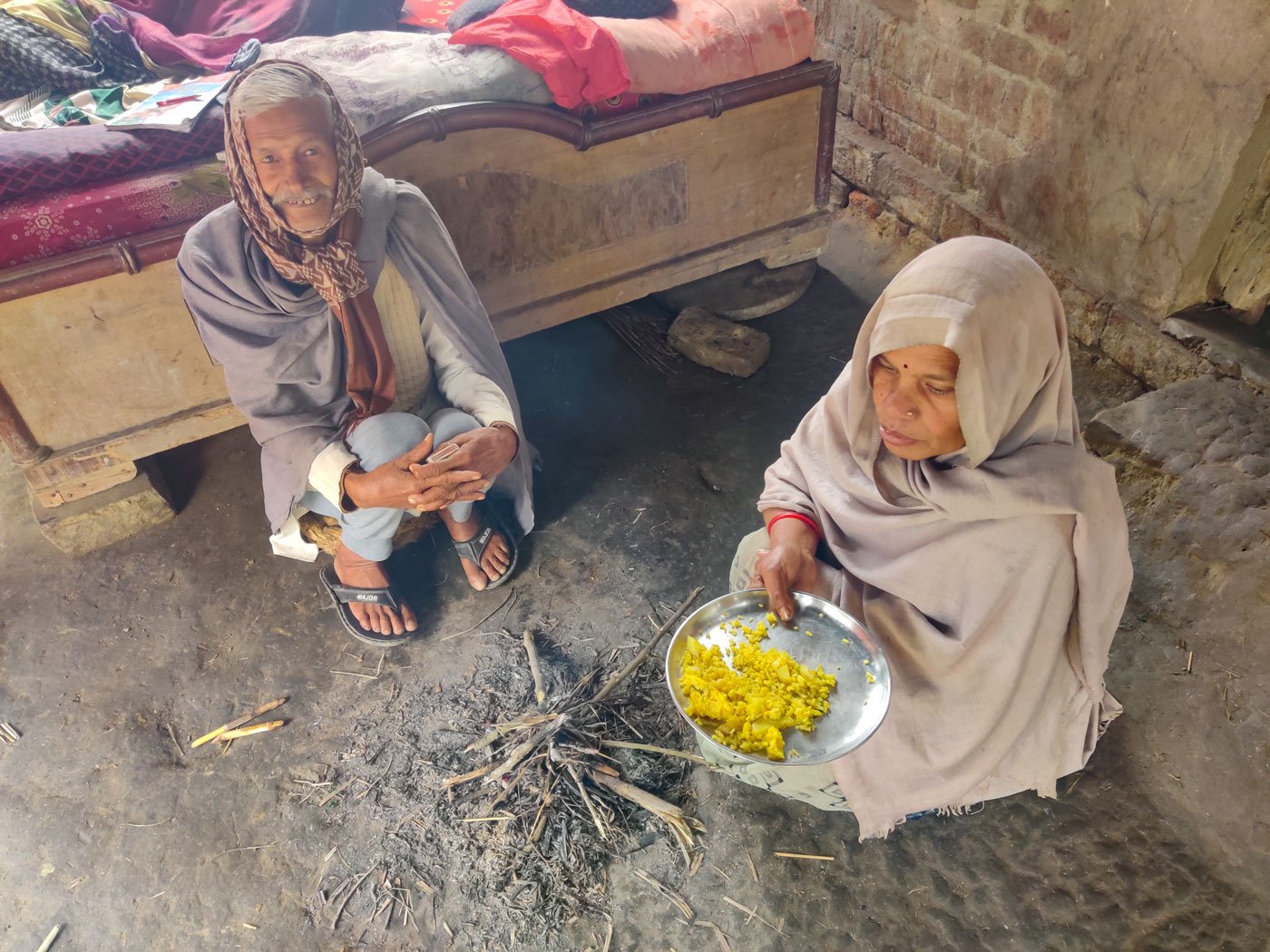 Srikrishna and his wife, Kanti, keeping warm by the fire. They mostly eat khichdi or dal rice as they have had to cut down on vegetables