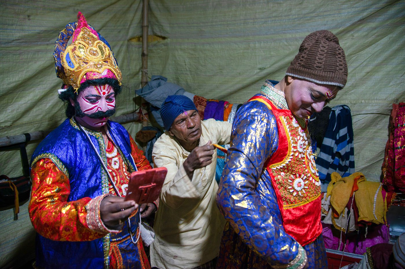 The green room is bustling with activity. A member of the audience helps an actor wear his costume