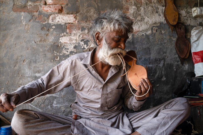 Hansraj has been practicing this craft for nearly half a century. He rolls the extra thread between his teeth before piercing the tough leather with the needle.
