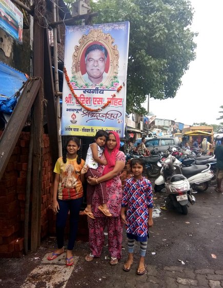 Granddaughter-in-law Tanu, wife of Bhateri Devi's deceased grandson Sanjay, with Sachi 11, Sara 8 and Saina 5. They are standing underneath the a garlanded poster of Bhateri Devi’s son, Sanjay’s father.