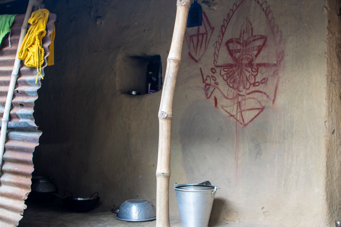 Built under the Pradhan Mantri Awas Yojana, Laxmi's house has a small pond in the backyard (left), and a kitchen with tarpaulin and tin walls and a mud floor (right)