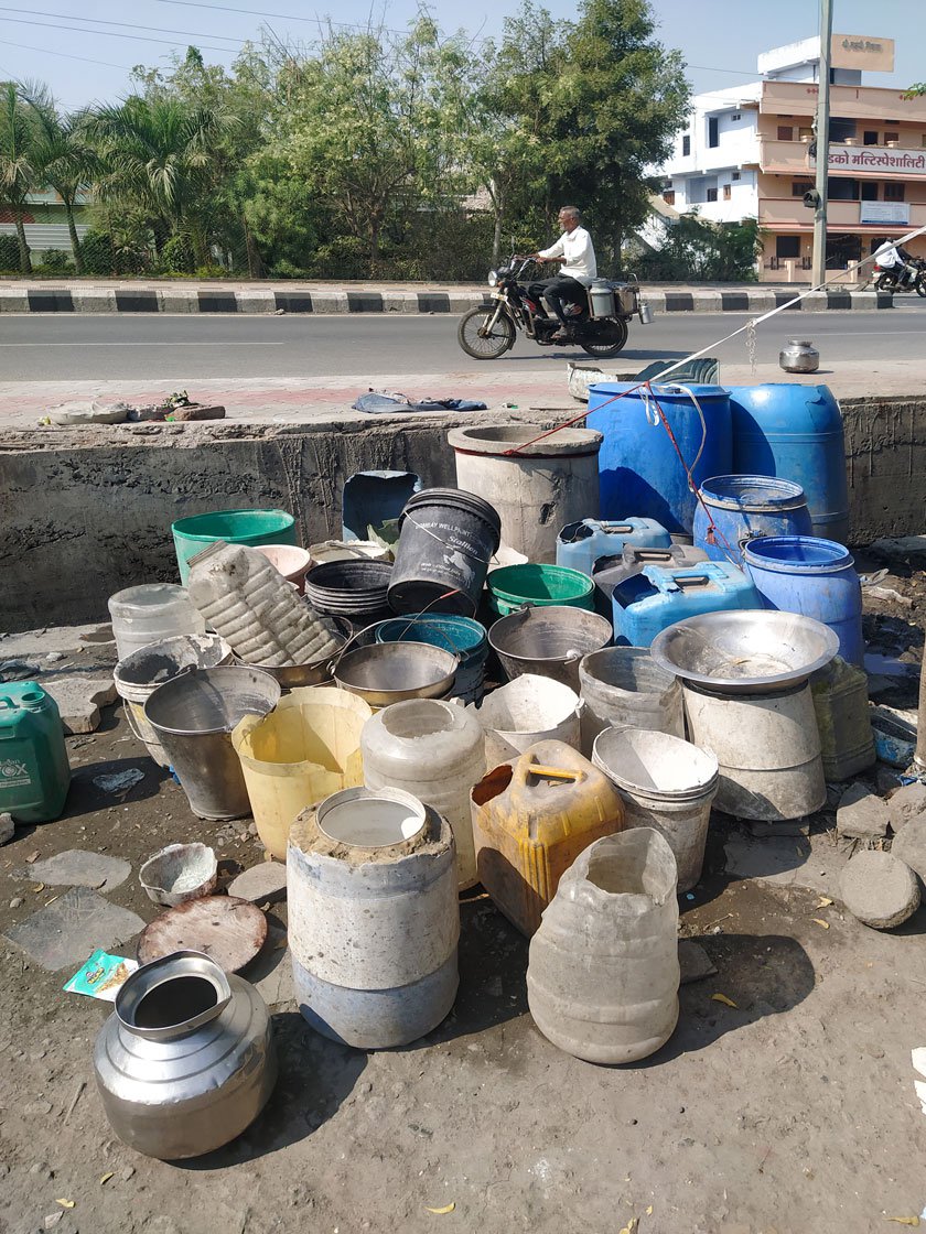 A collection of containers lined up to collect water. Their temporary homes on the side of a road (right)