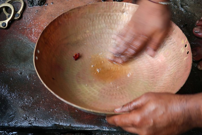 Sunil rubs tamarind on the kadhai to bring out the golden shine. He follows it up after rubbing diluted acid