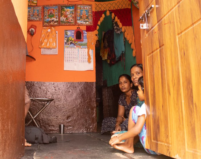 Gayathri and a neighbour sitting in her house. The 7.5 x 10 feet windowless home has no space for a toilet. The absence of one has affected her health and brought on excruciating abdominal pain.