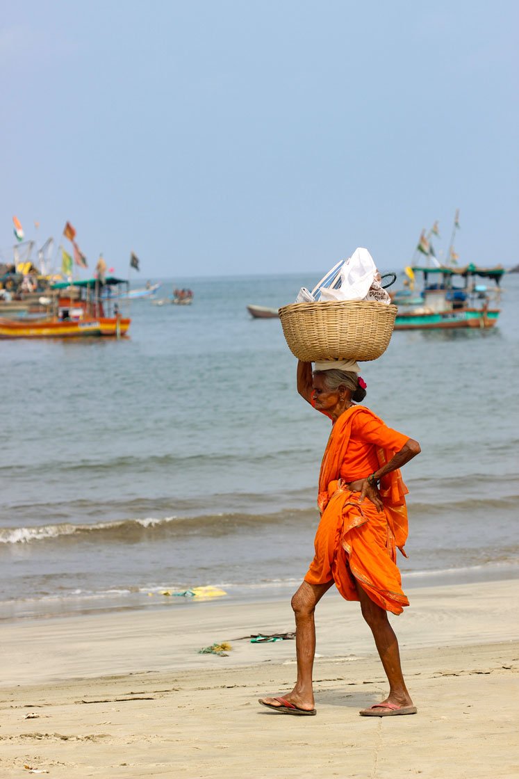 Left: 'We need to do something to fill our stomachs', says an elderly fisherwoman, as she walks a kilometre across Dandi beach in Malwan to the auction site to sell her family’s catch of tarli (sardine). Right: Women wash the fish to be to be salted and sun-dried 

