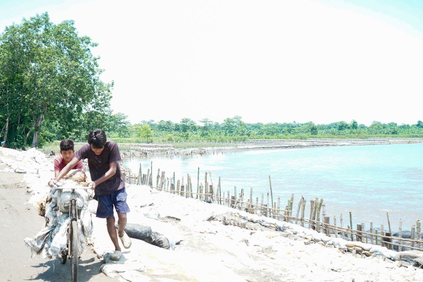 Left: Workmen from Bagribari placing sandbags below the embankment on the Puthimari river .