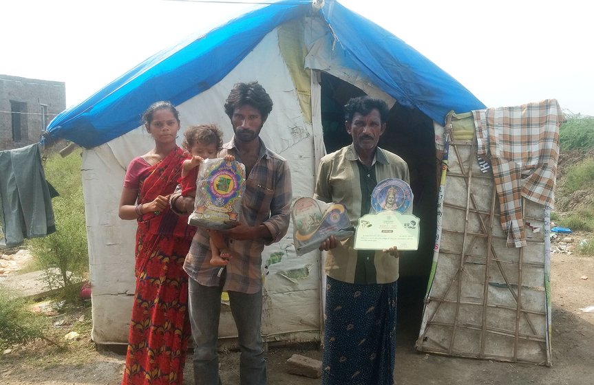 Rekhanara Kotilingam with his son and daughter in law, showing mementos won by his troupe in front of his house