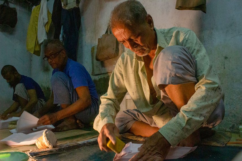 Mustansir Ujjaini (right) and two others working, seated on the floor