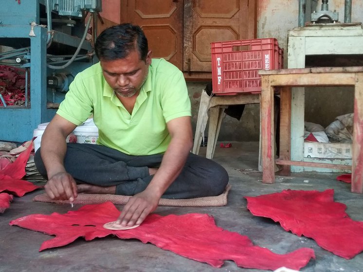 Sachin, 35, (right) cuts the leather in circles for two-piece balls