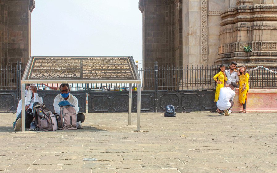 'Now no one looks at us, it’s as if we don’t exist', says Gangaram Choudhary. Left: Sheltering from the harsh sun, along with a fellow photographer, under a monument plaque during a long work day some months ago – while visitors at the Gateway click photos on their smartphones