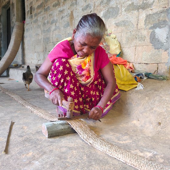 A long knife, a block of wood and a hammer help Jolen in achieving a clean cut. She uses a thick needle and plastic thread to stitch (right) the woven strips together