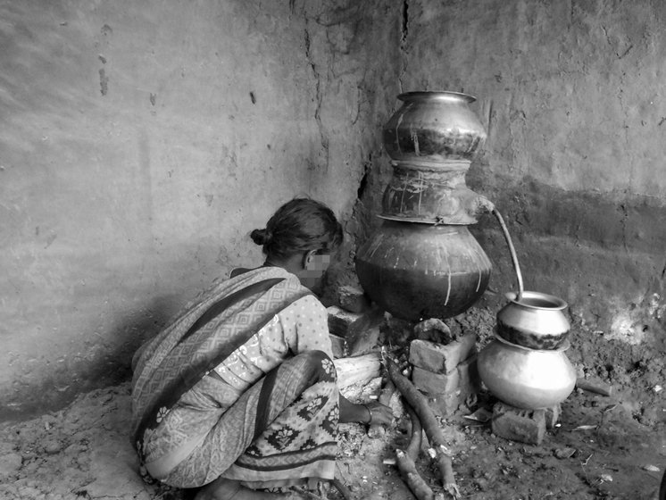 Motilal Kumar’s mother Koeli Devi checking the stove to ensure the flames reach the handi properly. The entire family works to distil the mahua daaru.