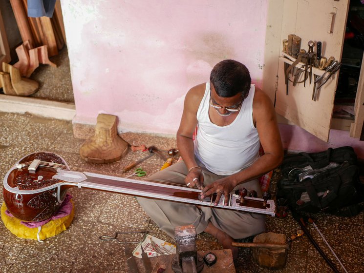 Left: Gaus Sitarmaker is setting the metal pegs on the sitar, one of the last steps in the process. The pegs are used to tune the instrument.