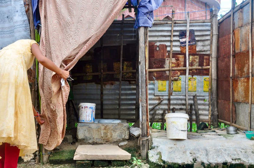 Left: Pushpa Kumari holding up the curtain to her family's toilet cubicle. Right: In the Sagaddi Masjid Road colony, a flimsy toilet stands in front of each house