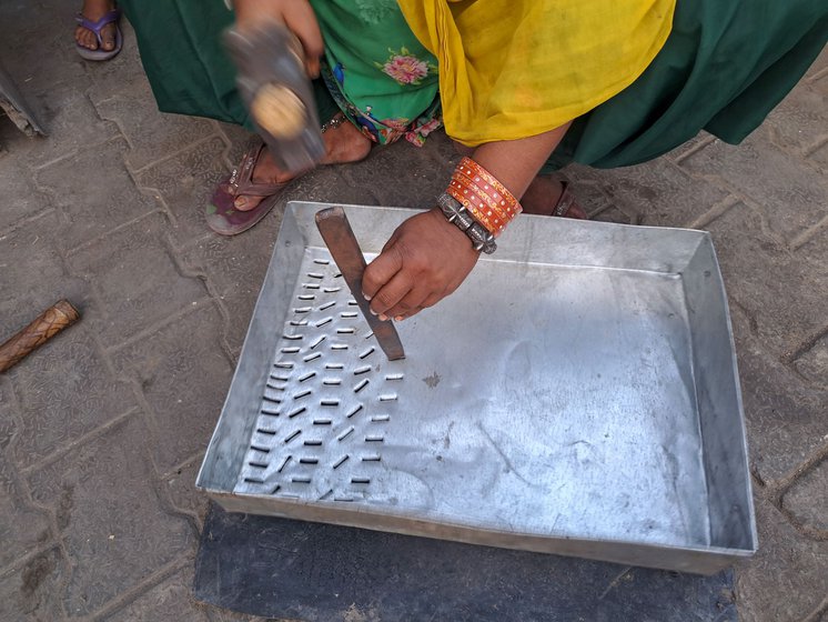 Salma uses a hammer and chisel to make a sieve which will be used by farmers to sort grain. With practiced ease, she changes the angle every two strikes