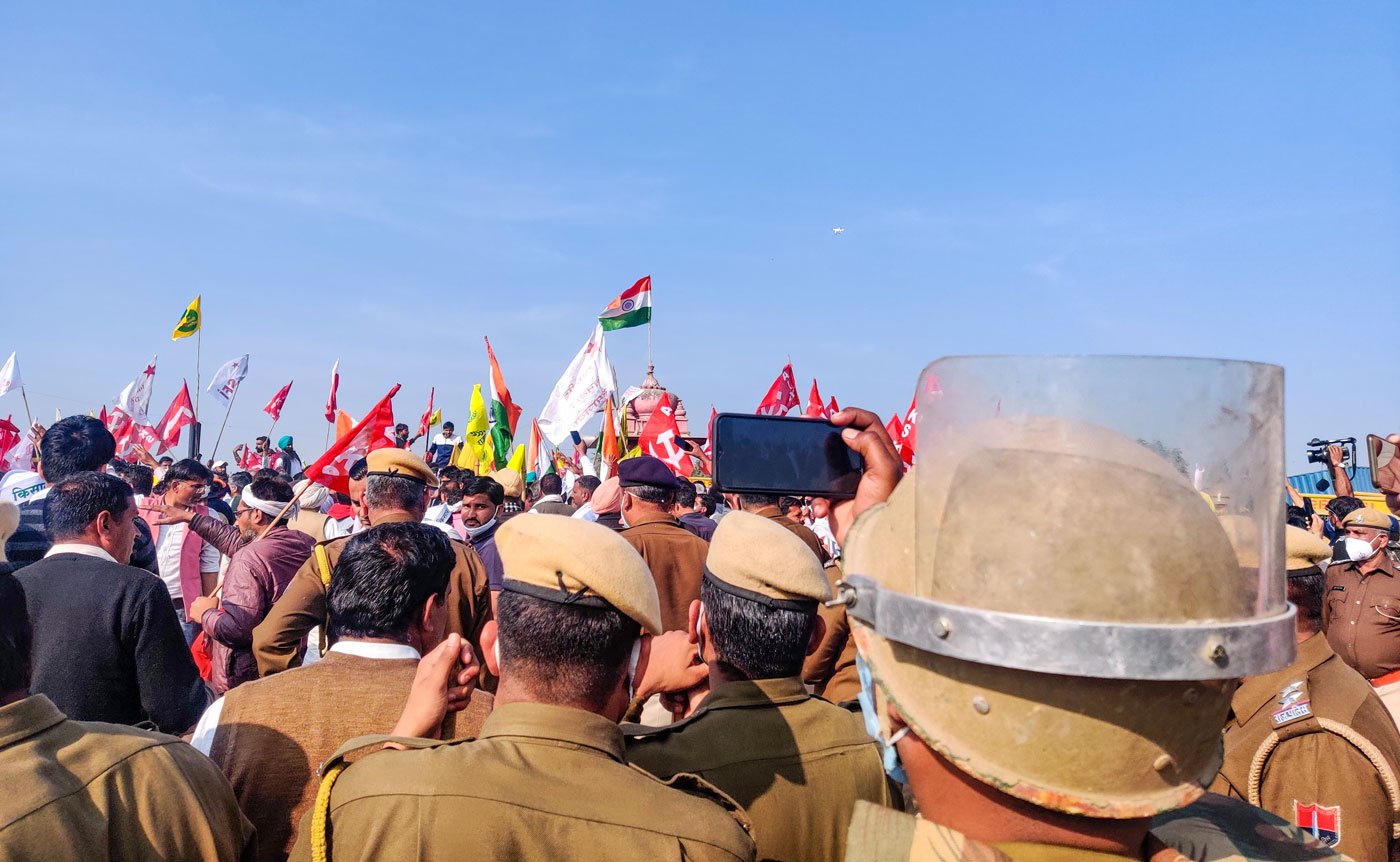 Left: Farm leaders walked up to the barricades upon arriving in Shahjahanpur. Right: A policeman quickly takes a photo