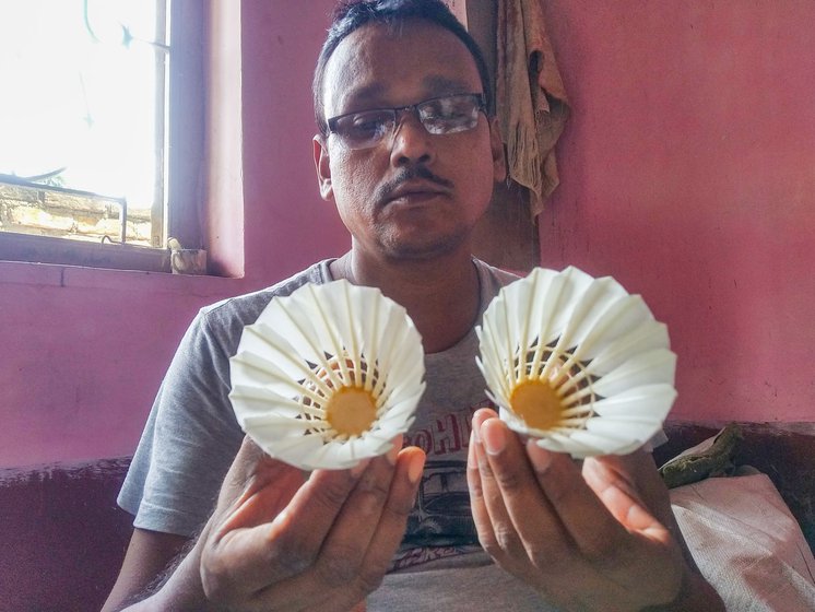 Right: Sanjib Bodak is holding two shuttles. The one in his left hand is made of feathers from the left wing of ducks and the one in his right hand is made of feathers from the right wing of ducks