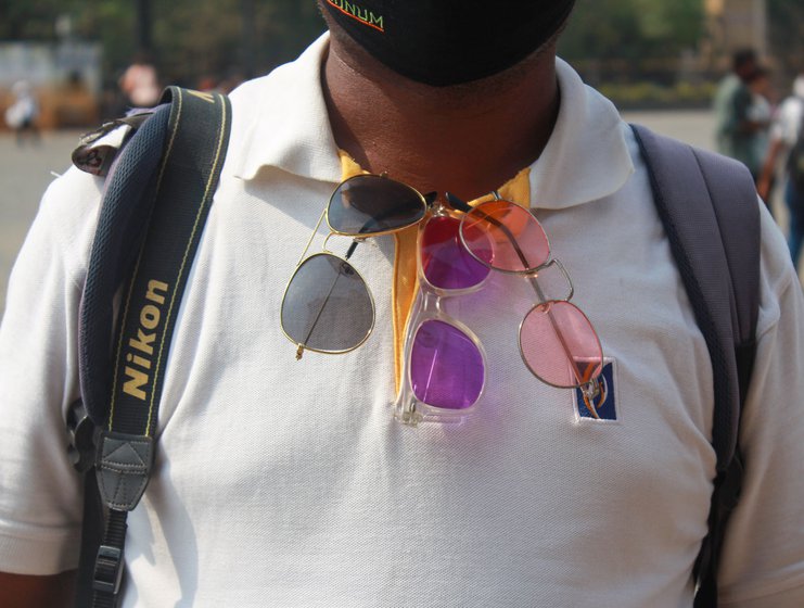 Tools of the trade: The photographers lug around 6-7 kilos – camera, printer, albums, packets of paper; some hang colourful sunglasses on their shirts to attract tourists who like to get their photos clicked wearing stylish shades