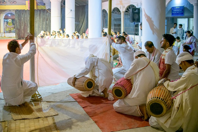 Khol, an asymmetric drum played by the bayan is central to the performance. A screen is held up as the group, along with their mentors, offers a prayer before beginning.