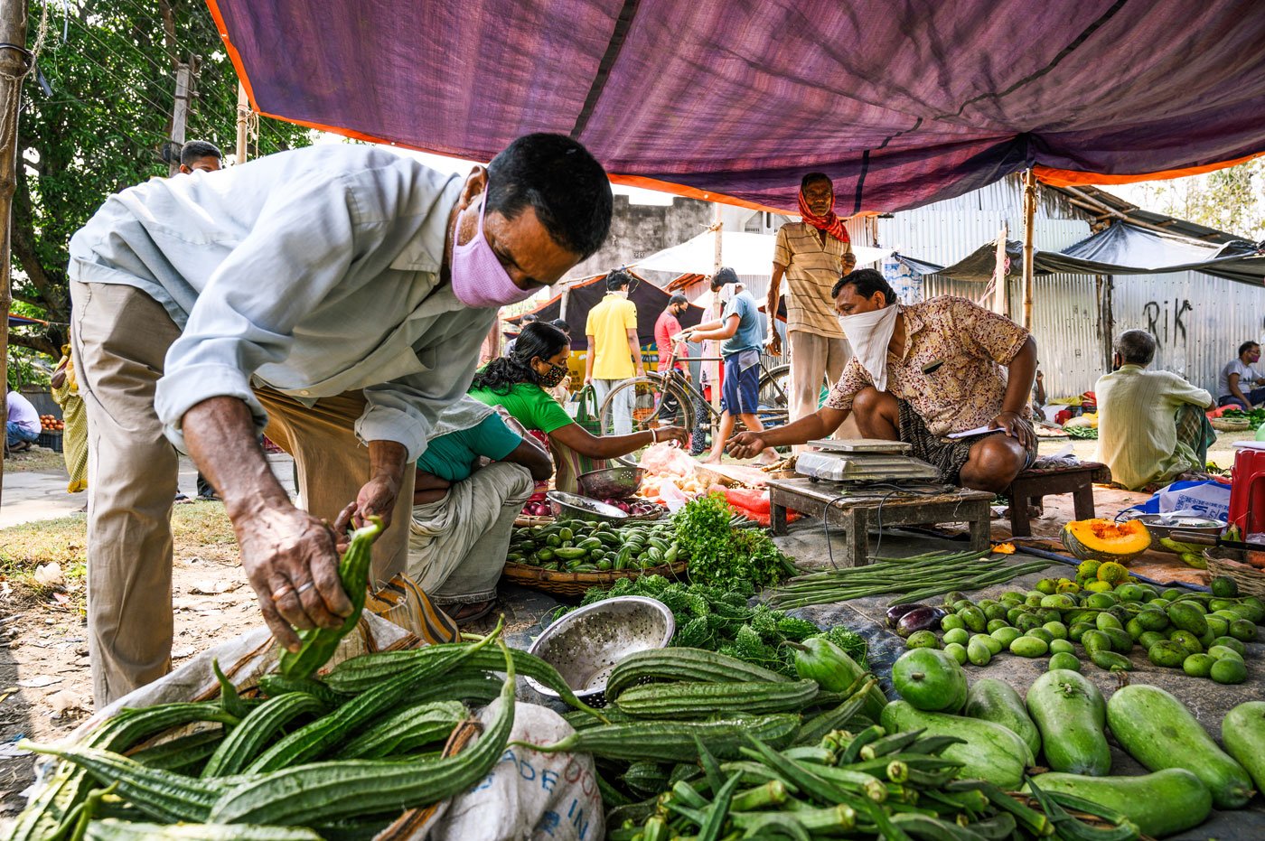 Customers picking up vegetable from Parimal Dalal’s stall. After 30 years of doing this work, 51-year-old Parimal, is more confident than the others, and says, "My business hasn't changed much. Customers I am acquainted with are coming here too."