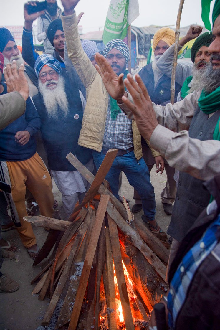 Left: Posters announcing that the three farm laws will be burnt at 7 that evening on the occasion of Lohri. Right: Farmers raise slogans as the Lohri fire burns.