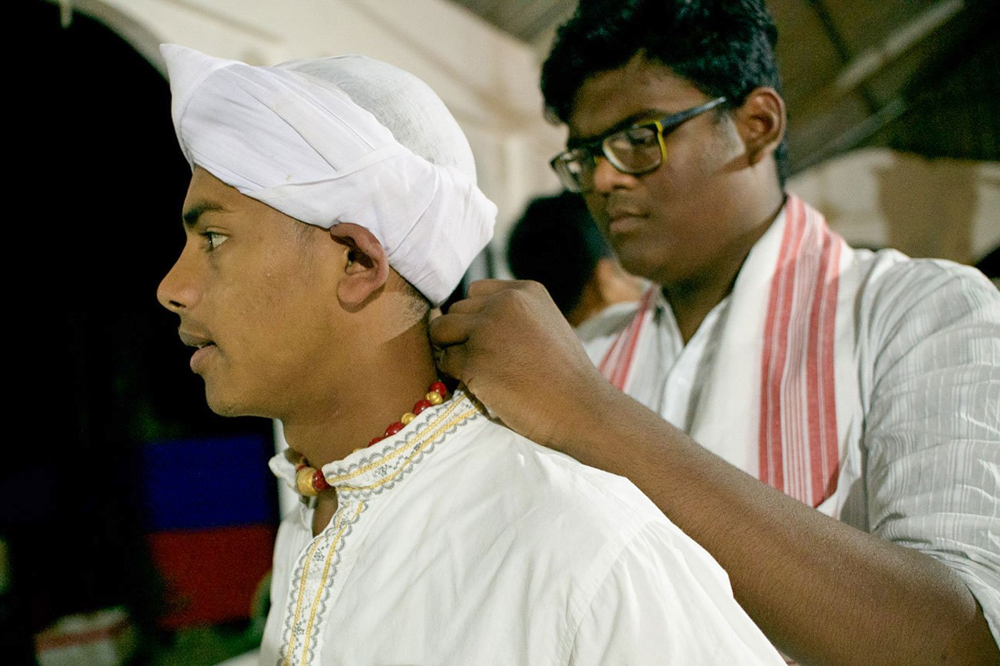Xuruj, a gayan in the group, arranges the motamoni mala around the neck of his fellow artist Subhashish