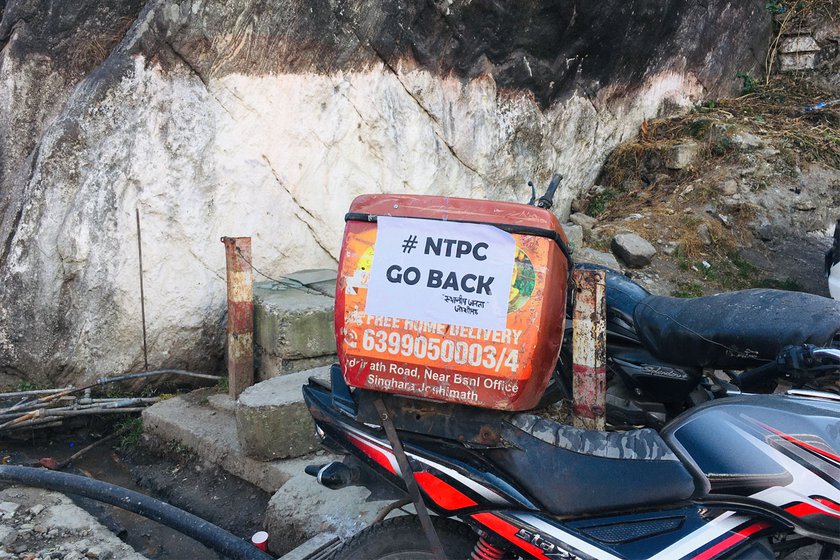 he people of the town are holding sit-in protests agianst the tunneling and drilling which they blame for the sinking. A poster saying 'NTPC Go Back'  pasted on the vehicle of a local delivery agent.