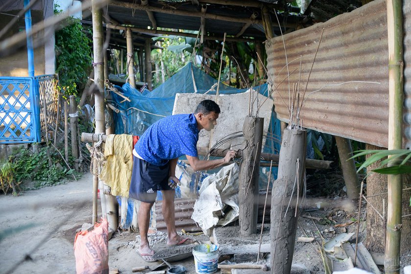 The artist works on a pair of sculptures outside his home. The Joy-Bijoy figures are said to be guards to namghars . He makes such sculptures using wooden frames and concrete, and later paints them using fade-proof plastic paints