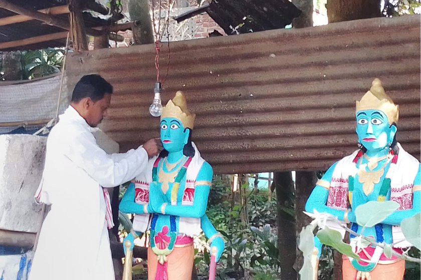 The artist works on a pair of sculptures outside his home. The Joy-Bijoy figures are said to be guards to namghars . He makes such sculptures using wooden frames and concrete, and later paints them using fade-proof plastic paints