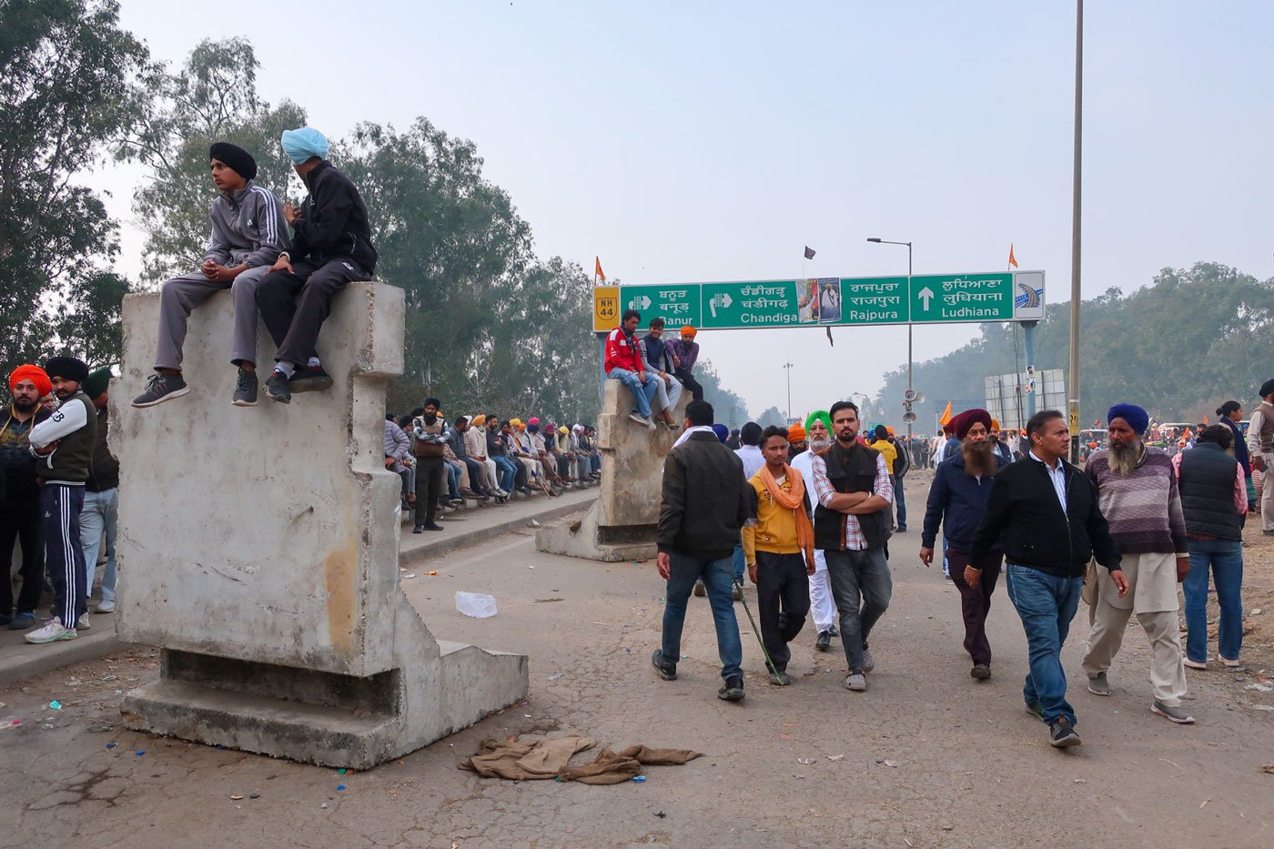 Protesters sit on the concrete barricades, facing Haryana