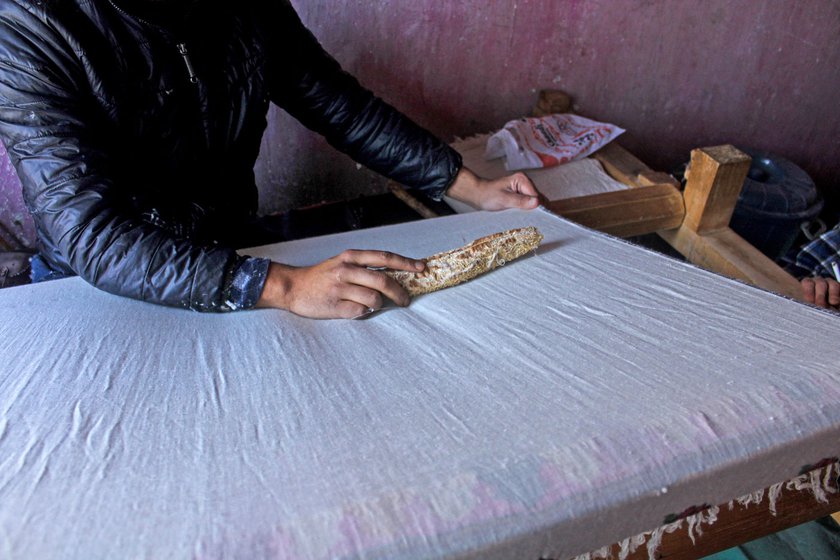 A purazgar brushes over a pashmina shawl with a dried bitter gourd shell to remove purz plucked with a wouch