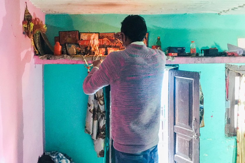 The photos of gods have not been packed away. Raghav is standing on a chair in the makeshift kitchen as he prays for better times.