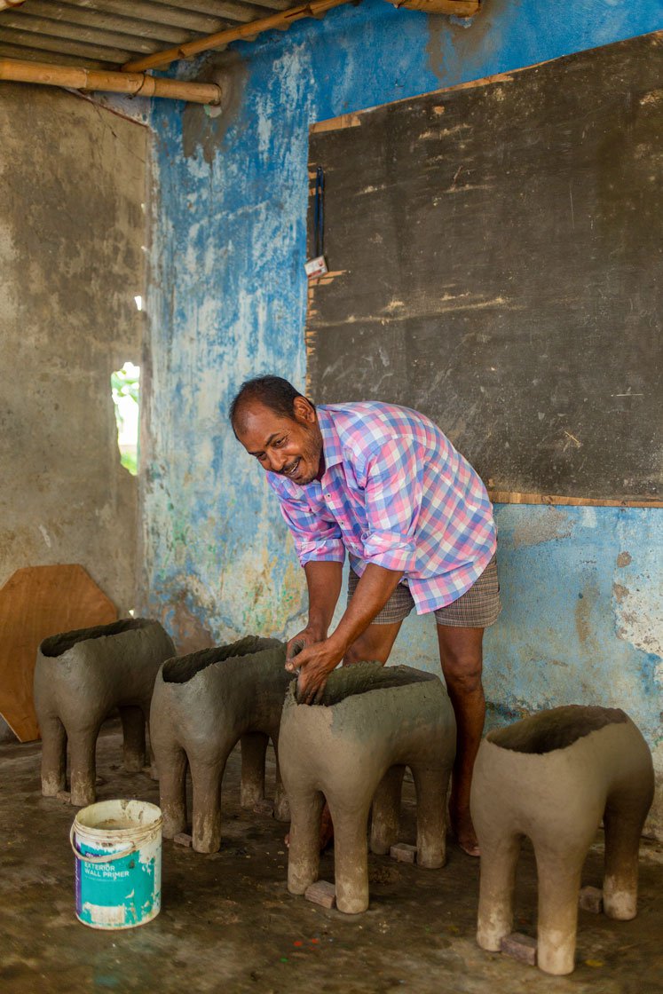 The idol maker applying another layer of the clay, hay and husk mixture to the base of the idols. ' This entire work has to be done in the shade as in in direct sunlight, the clay won’t stick, and will break away. When the idols are ready, I have to bake then in fire to get it ready'