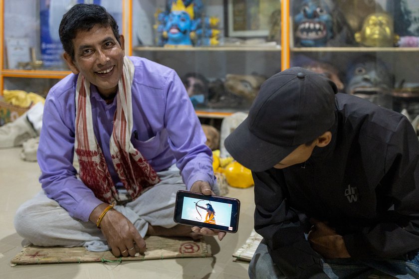 Right: Dhiren and Goutam showing a bollywood music video three mask makers from Majuli performed in. The video has got over 450 million views on Youtube