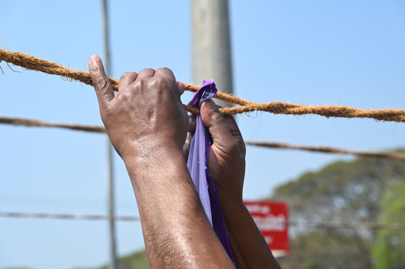 Rajan carefully tucking clothes between the ropes to keep them in place