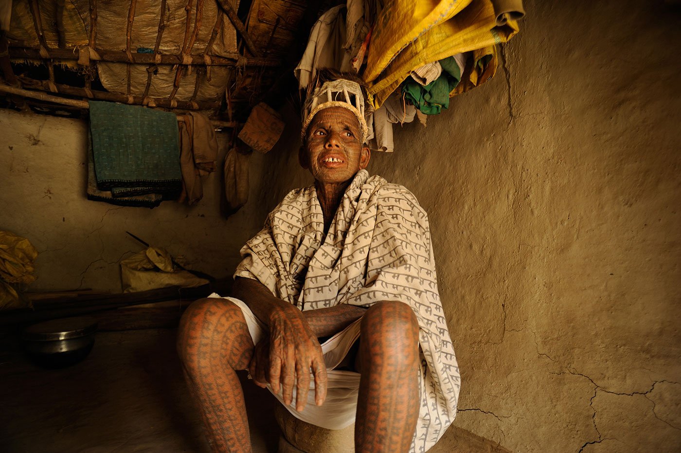 Old tattooed woman sitting in her mud house 